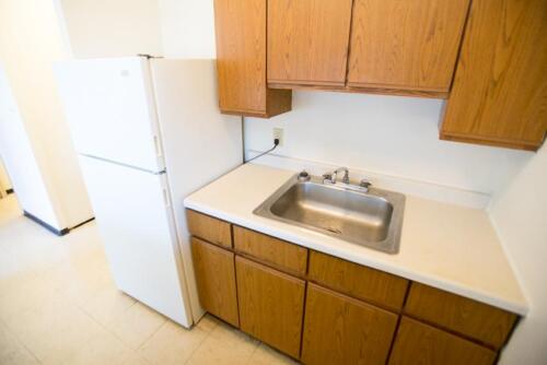An empty kitchen with wooden cabinets and a sink.